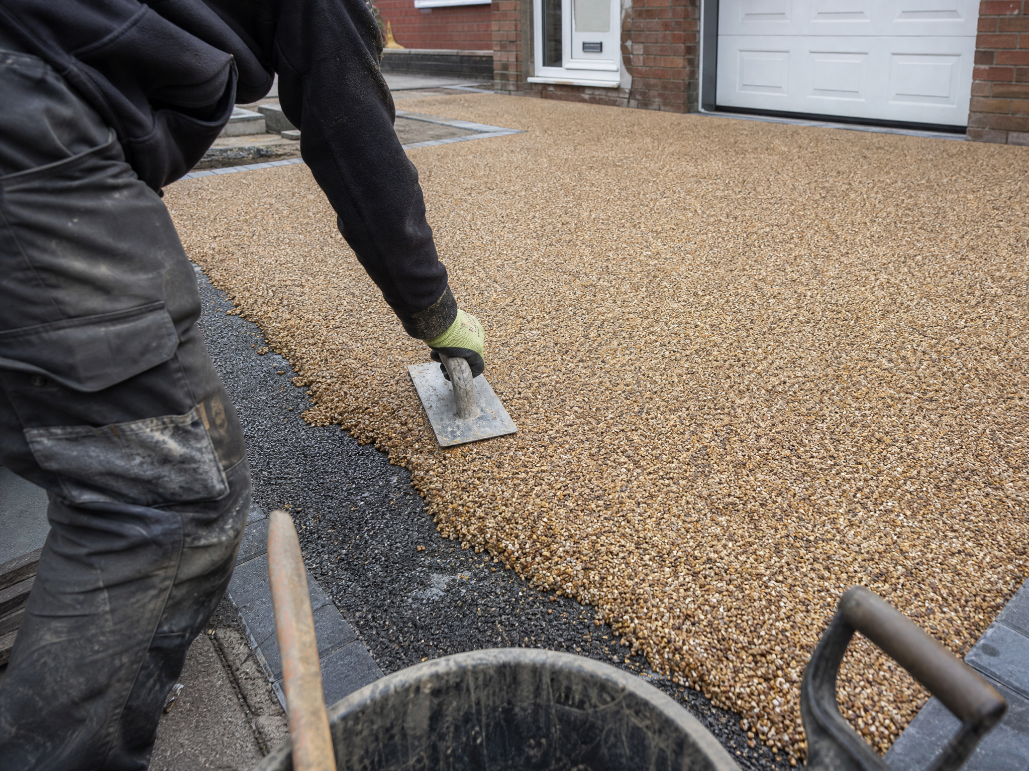 Professional installer carrying out resin bound driveways in a British residential property