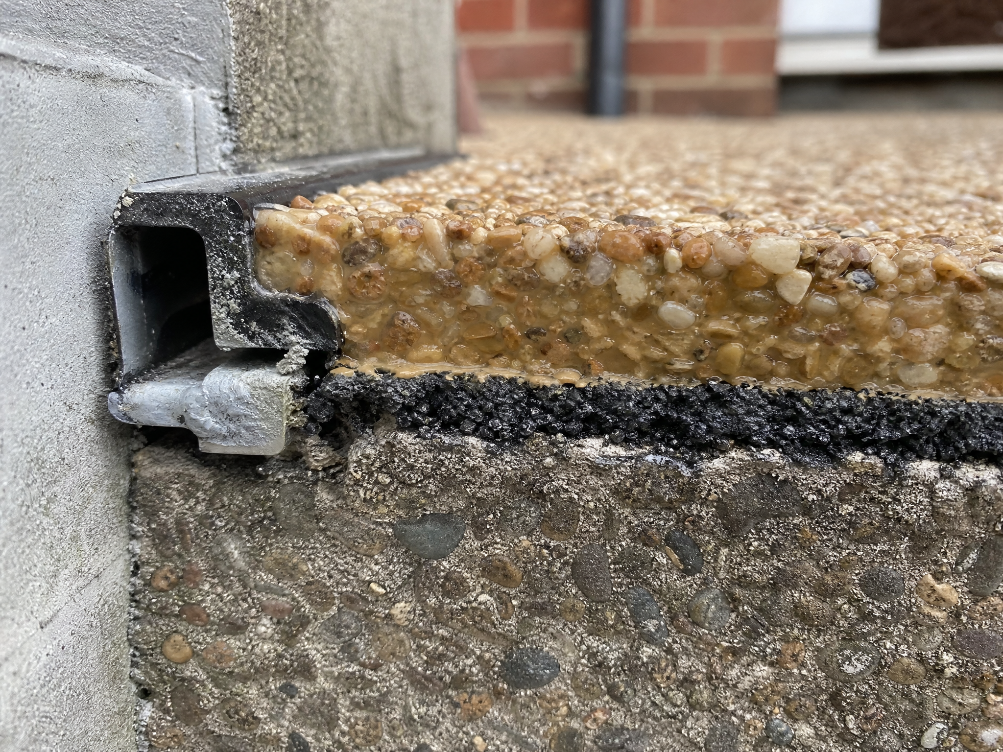 Close-up detail of materials and technique used in resin over tarmac & concrete — showing quality