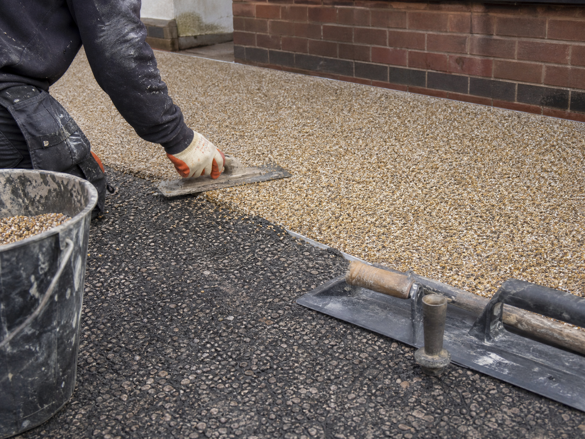 Professional installer carrying out resin over tarmac & concrete in a British residential property